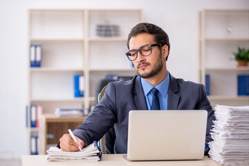 Obraz premium Young male employee and too much work in the office