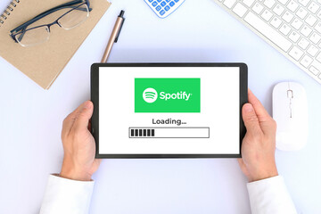 Obraz na płótnie Canvas Man hand used tablets on desk office with Spotify logo on the screen 24 March 2022 of thailand