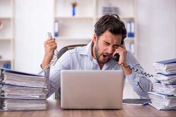 Young male employee unhappy with excessive work in the office