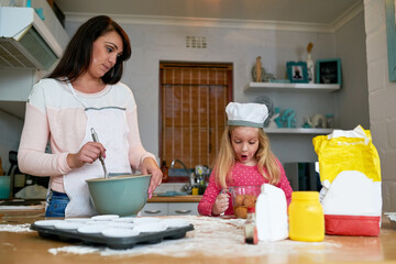 Teaching her daughter the baskics of baking. Cropped shot of a little girl baking in the kitchen with her mom.
