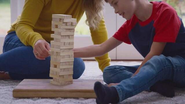 Mother and son at home playing game stacking and balancing wooden blocks together - shot in slow motion
