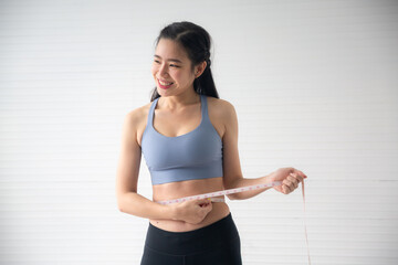 young Asian woman measure body proportions, health fitness to slim body concept
