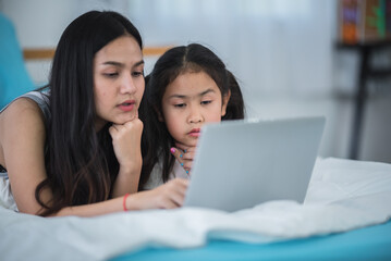 mother teaching child girl for doing homework at home, family education activity concept