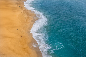 Beautiful turquoise blue waters and yellow sand at Nazaré beach - Portugal