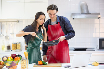 young couple person having fun and happy to cook a healthy food meal in home kitchen