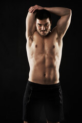 Your limits are smaller than you think so keep pushing. Studio portrait of a sporty young man stretching his arms isolated on black.