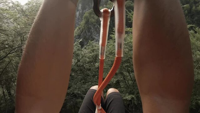Point of view slacklining on a valley. High and scary view down. A unique perspective of nature from a zip line in a canyon. View on forest and river from a bird view.