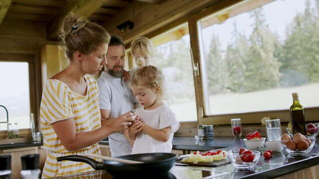 Mother blowing her little daughter's bleeding finger cut with knife at home.