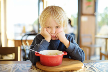 Little child sitting the table in cafe or restaurant and doesn't want to eat. Healthy food. Kids...