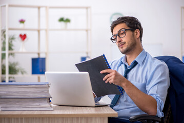 Fototapeta premium Young businessman employee and too much work in the office