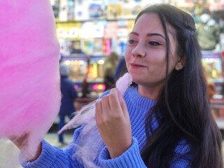 Girl looking as if she is enjoying while eating a cotton candy at night