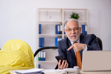 Old male employee looking after new born at workplace