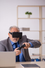 Old male employee enjoying virtual glasses at workplace
