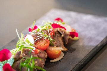 Close up to Spicy Thai Beef Salad garnished on top with cress and micro herb was put on a rectangular stone plate.