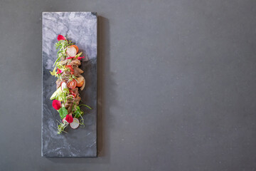 Flat lay of Spicy Thai Beef Salad garnished on top with cress and micro herb was put on a rectangular stone plate. Clipping Path.