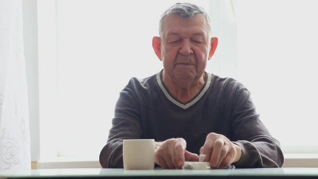 Portrait of elderly man. Senior takes pills sitting at table. High quality photo