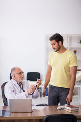Fototapeta premium Young male patient visiting old male doctor
