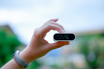 Woman's hand holding air pollution monitor PM 2.5 concept, fresh air life.