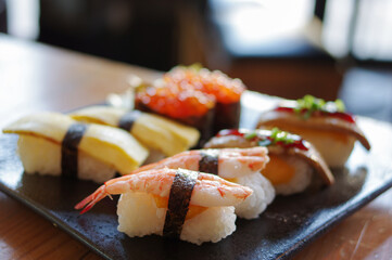 nigiri sushi with shrimp nori tamago egg salmon roe foie gras on black plate
