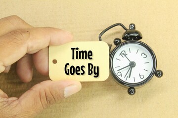 an alarm clock and a wooden tag with the words time goes by