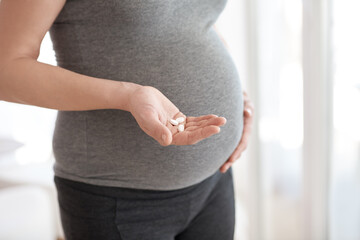 Prenatal vitamins are important for proper development. Cropped shot of a pregnant woman holding tablets while standing in her home.