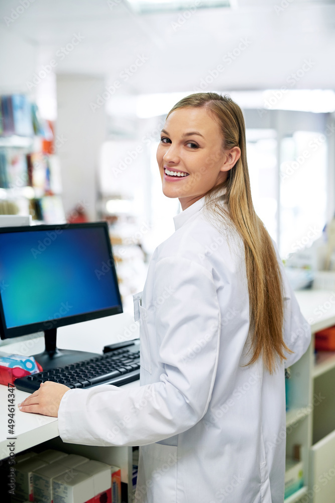 Poster Keeping track of orders with technology. Shot of a young pharmacist using a computer at the checkout counter.
