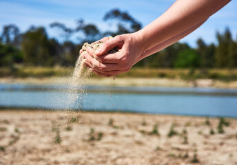We are on our last bit of water. Shot of an unrecognizable person holding two hands full of sand showing how dry the area is outside.