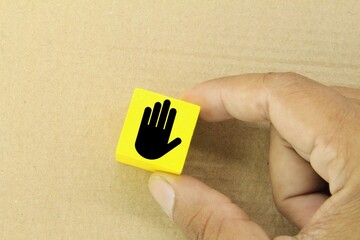 the hand holds a yellow cube with a stop signature