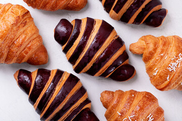 Croissants with chocolate made of two-colored dough on the white table. Puff pastry dessert. Top...