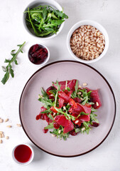 Salad with smoked duck breast, arugula, dried cranberry and pine nuts served on the ceramic plate. Exquisite cold appetizer. Top view