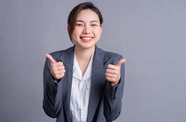 Portrait of a beautiful Asian businesswoman on a gray background