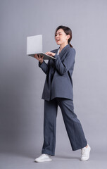 Young Asian business woman standing on gray background