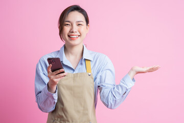 Young Asian waitress standing on pink background