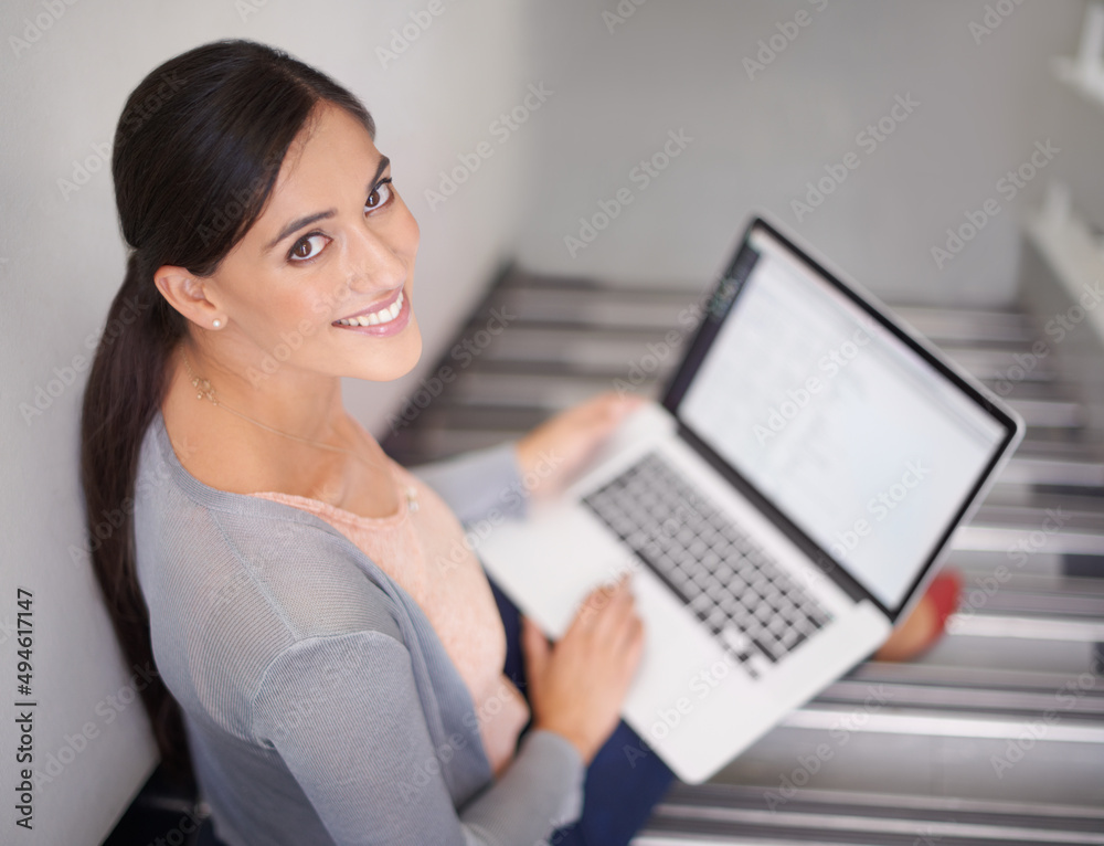 Poster getting some work in before class. portrait of a young woman sitting on stairs using a laptop.