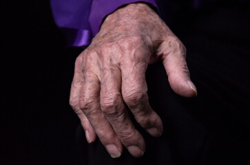 Fototapeta premium Hands of an elderly woman on a black background, the concept of old age. 