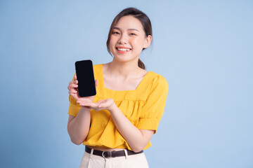 Young Asian girl using smartphone on blue background