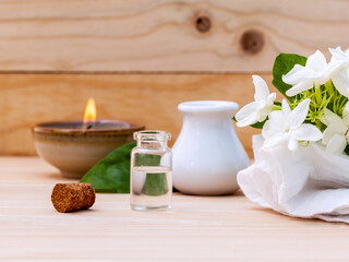 Fototapeta na wymiar Aroma oil bottles arranged with jasmine flowers on wooden background .