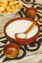 Koumiss milk drink in a wooden bowl with an ornament in the national Kazakh style on the table....
