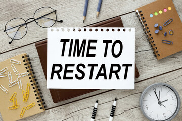 TIME TO RESTART text on a sheet of paper with text on a brown notepad