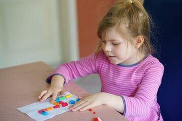 Little creative toddler girl making colorful giraffe with playmais. Active happy child having fun with drawing doing handicraft. Education for kids. Funny activity.