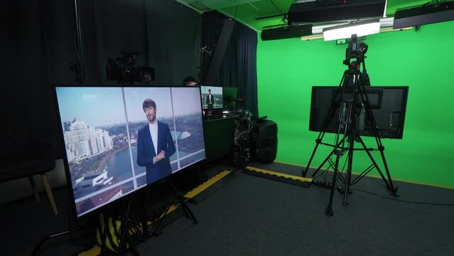 Backstage, news anchor at work, man reporter looks into the camera and talks, studio TV news shooting, view of the screens, live broadcast, chroma key template.