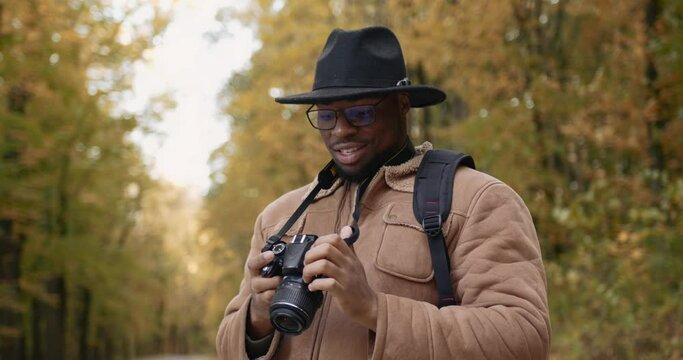 Traveler with a camera takes pictures of the autumn forest