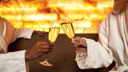 Cropped of girls toast champagne in glasses in spa