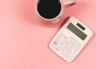 flat lay of pink calculator and pink cup of black coffee on pink background with copy space.