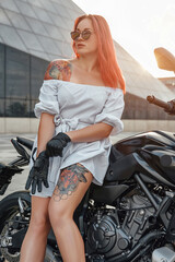 Fototapeta na wymiar Fashionable woman motorcyclist with custom motorbike outdoors in city