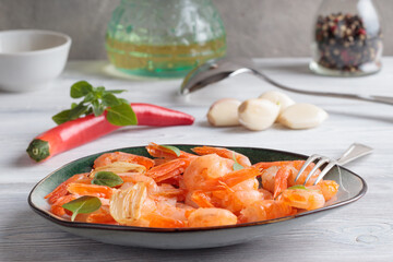 Close-up view of shrimps pinchos tapas from Spain in plate with fork, red pepper, garlic, oil on on white wooden rustic background. Selective focus.