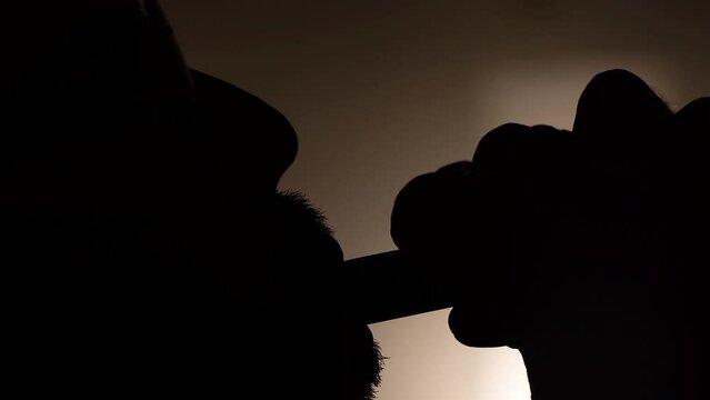 Extreme close up of a silhouette of a man vaping and blowing smoke (4K)