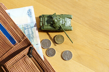 War in Ukraine and sanctions against Russia concept. Wallet with Russian rubles and a toy tank on a...