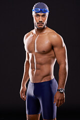 Fototapeta na wymiar Time to dominate the competition. Studio shot of a handsome swimmer against a black background.