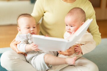 絵本を読む母親と双子の赤ちゃん